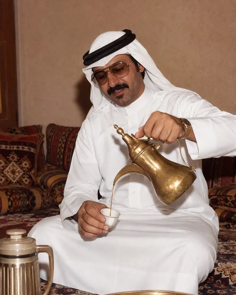 صبّ القهوة من الدلة يبقى كما هو، لكن الثوب والغترة والنظارة والترمس وصحن التمر كلها من عام 1986.