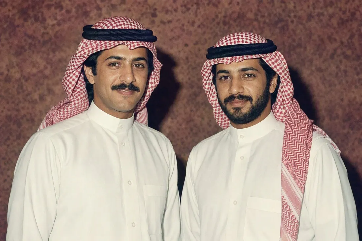 بورتريه استوديو من عام 1986 لأخوين بالغين بثوبين أبيضين وغترتين وعقالين أمام خلفية استوديو رمادية مزرقة بفلاش مباشر، بستايل الثمانينات من FaceCast