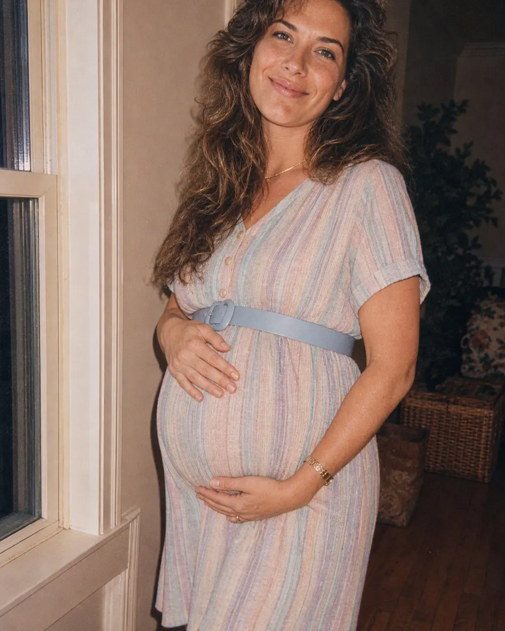 A pregnancy photo restyled as a mid-1980s maternity portrait with soft flash and film grain