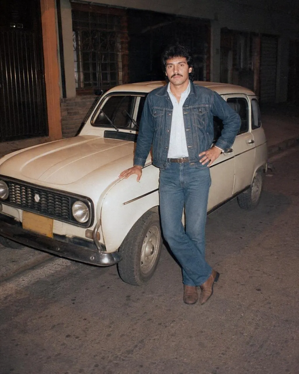 Retrato junto a un auto deportivo de los años 80 en una calle nocturna