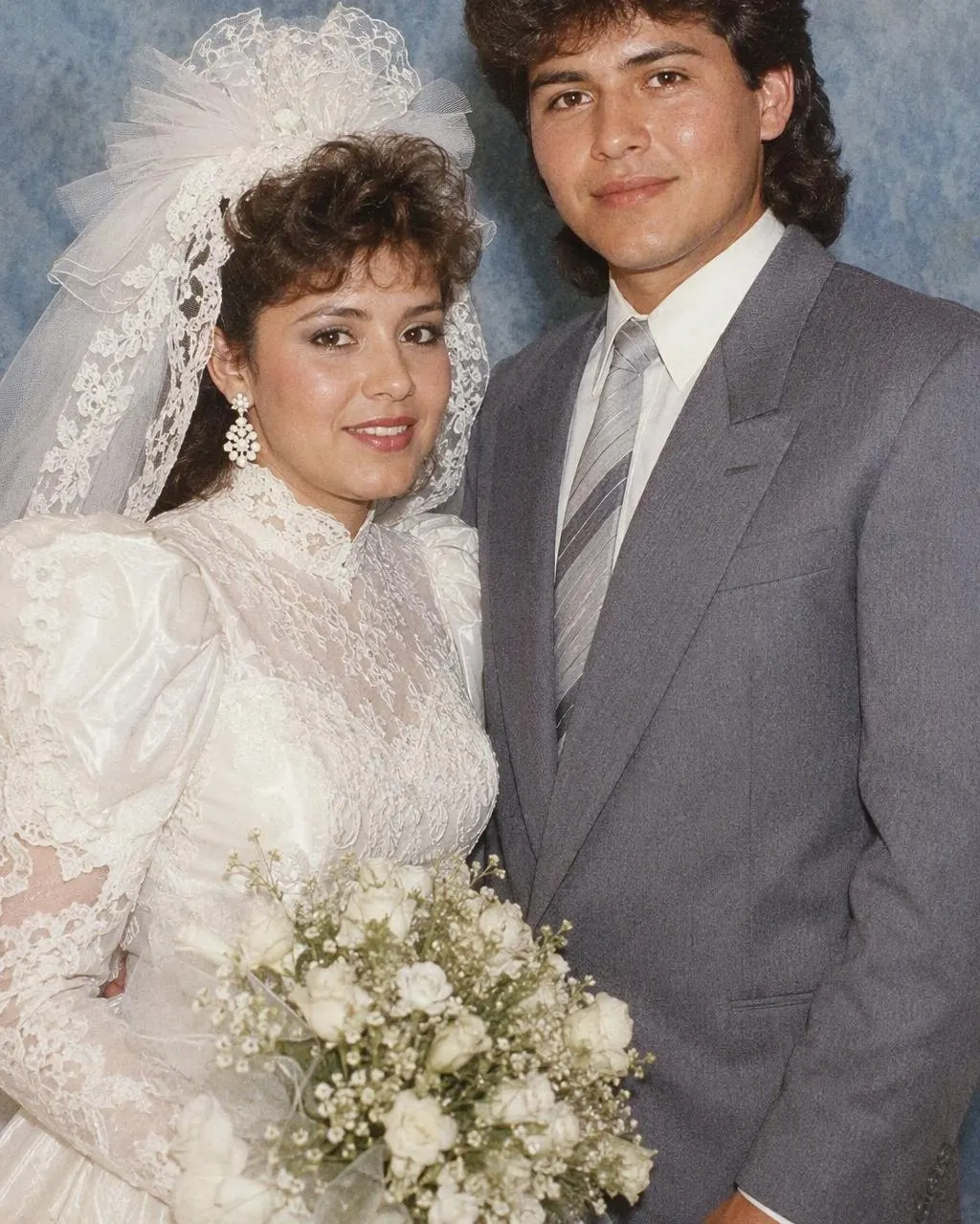 Pareja de novios con vestido de mangas abombadas y esmoquin de solapa ancha, en una foto de boda de los 80 generada con IA