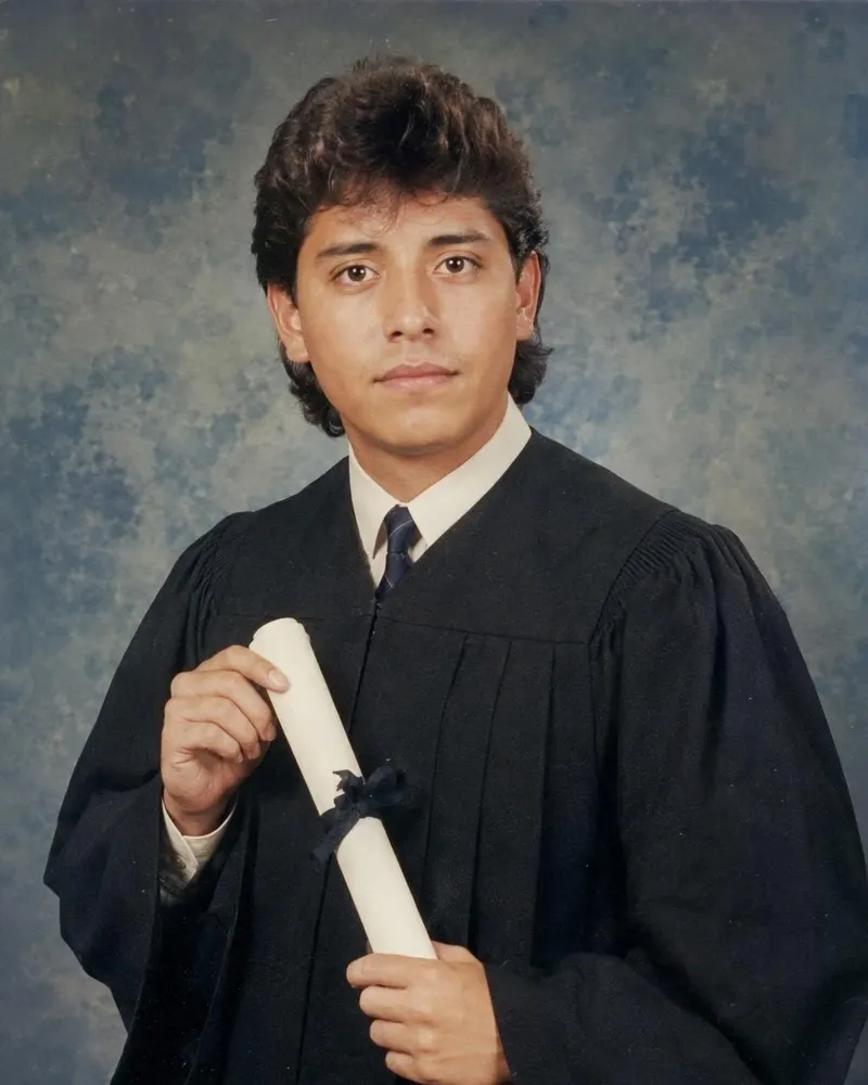 La toga y el birrete pasan a un retrato de estudio de graduación de los 80.