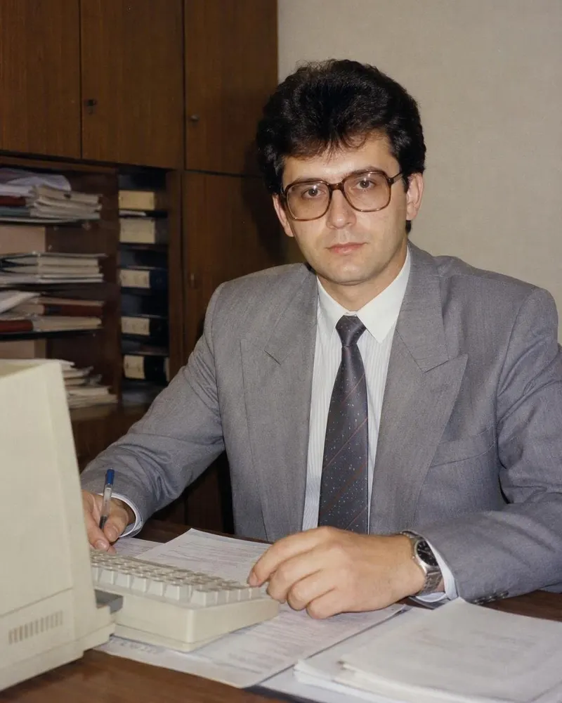 Portretul de la birou primește umeri lați și ochelari cu ramă mare.