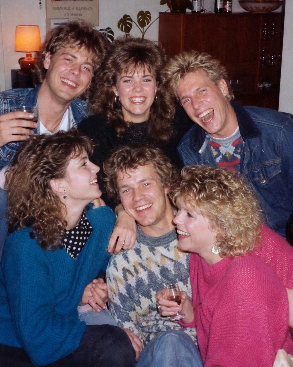 En gruppe venner i tøj fra midten af 80’erne til en hjemmefest med store frisurer og kraftige farver, lavet med FaceCast