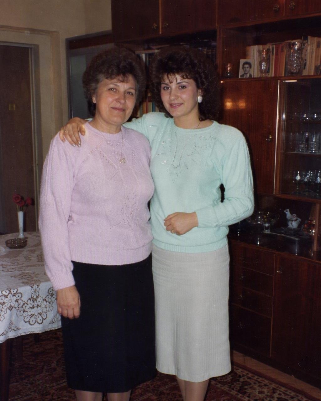 O mamă și fiica ei adultă transformate într-un portret de familie de studio de la mijlocul anilor 80, cu permanent și tricotaje pastel, făcut cu FaceCast