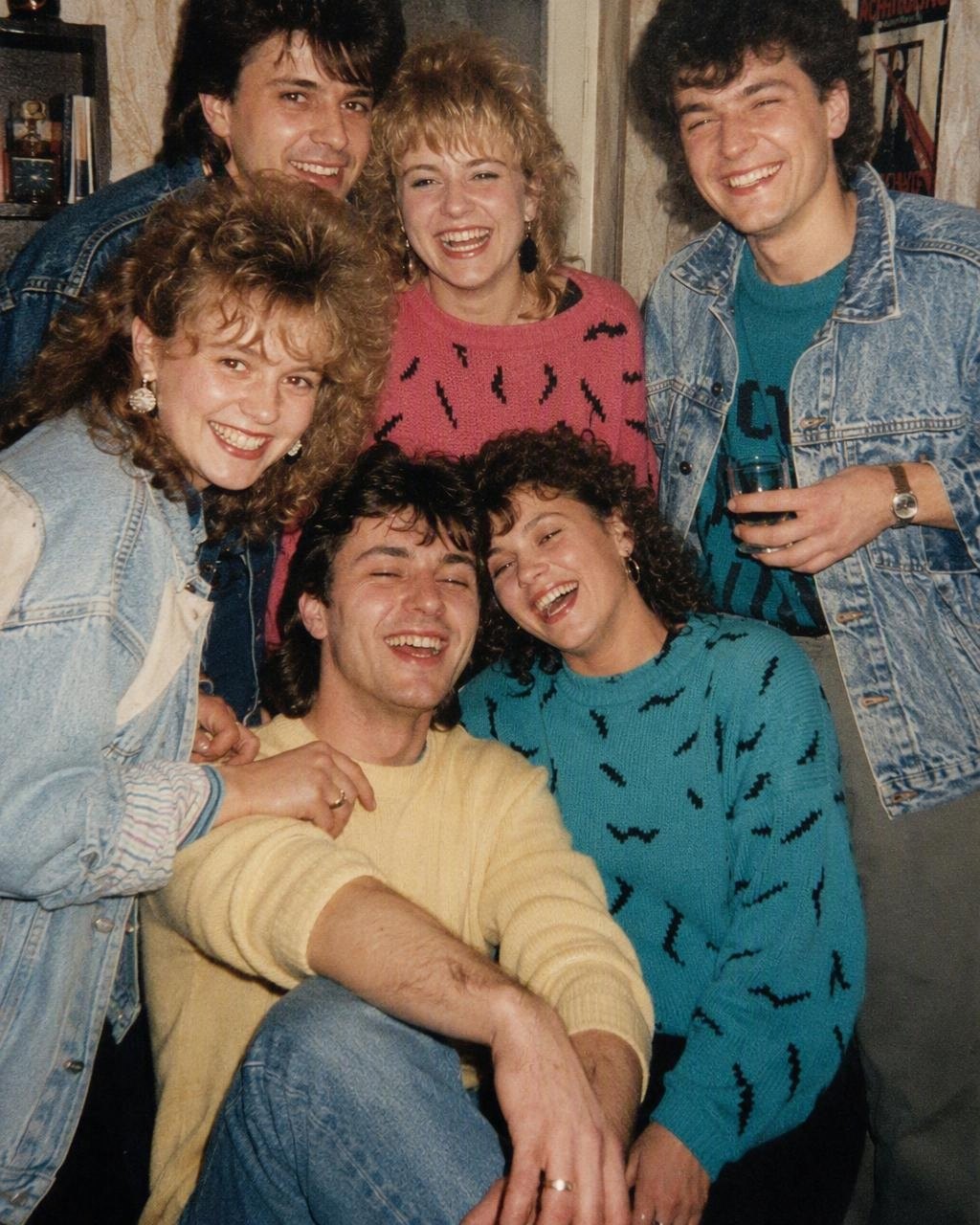 Un grup de prieteni la o petrecere de la mijlocul anilor 80, cu păr voluminos și culori tari